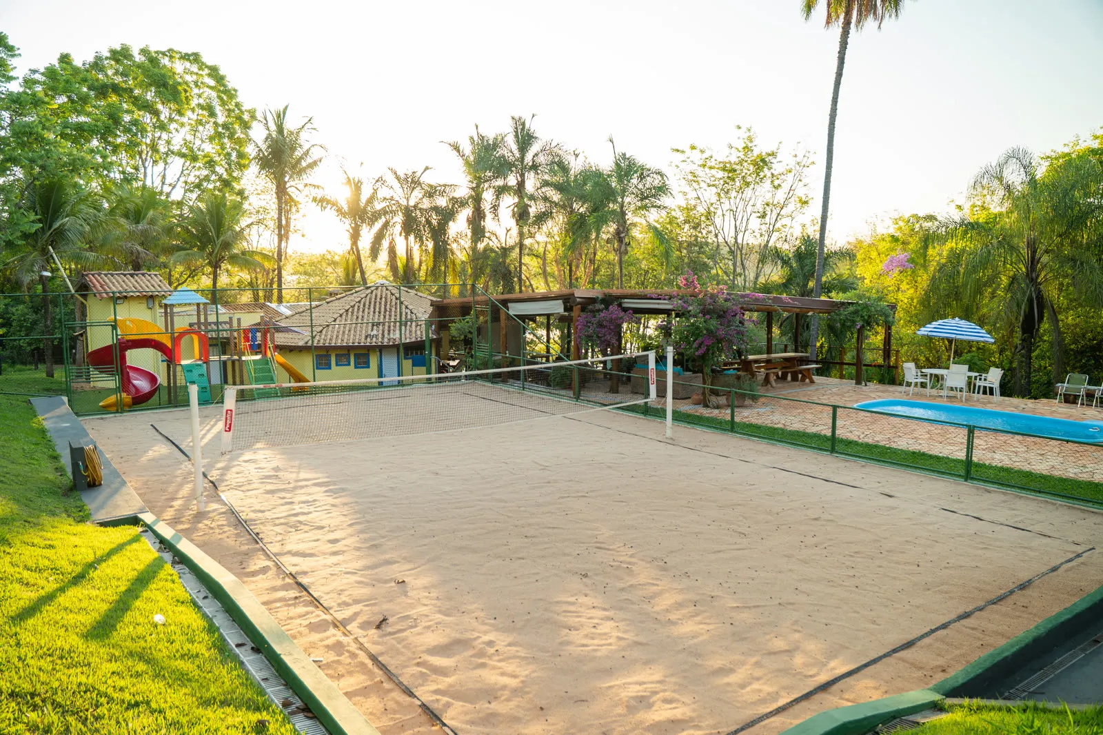 Quadra de areia com playground e piscina ao lado