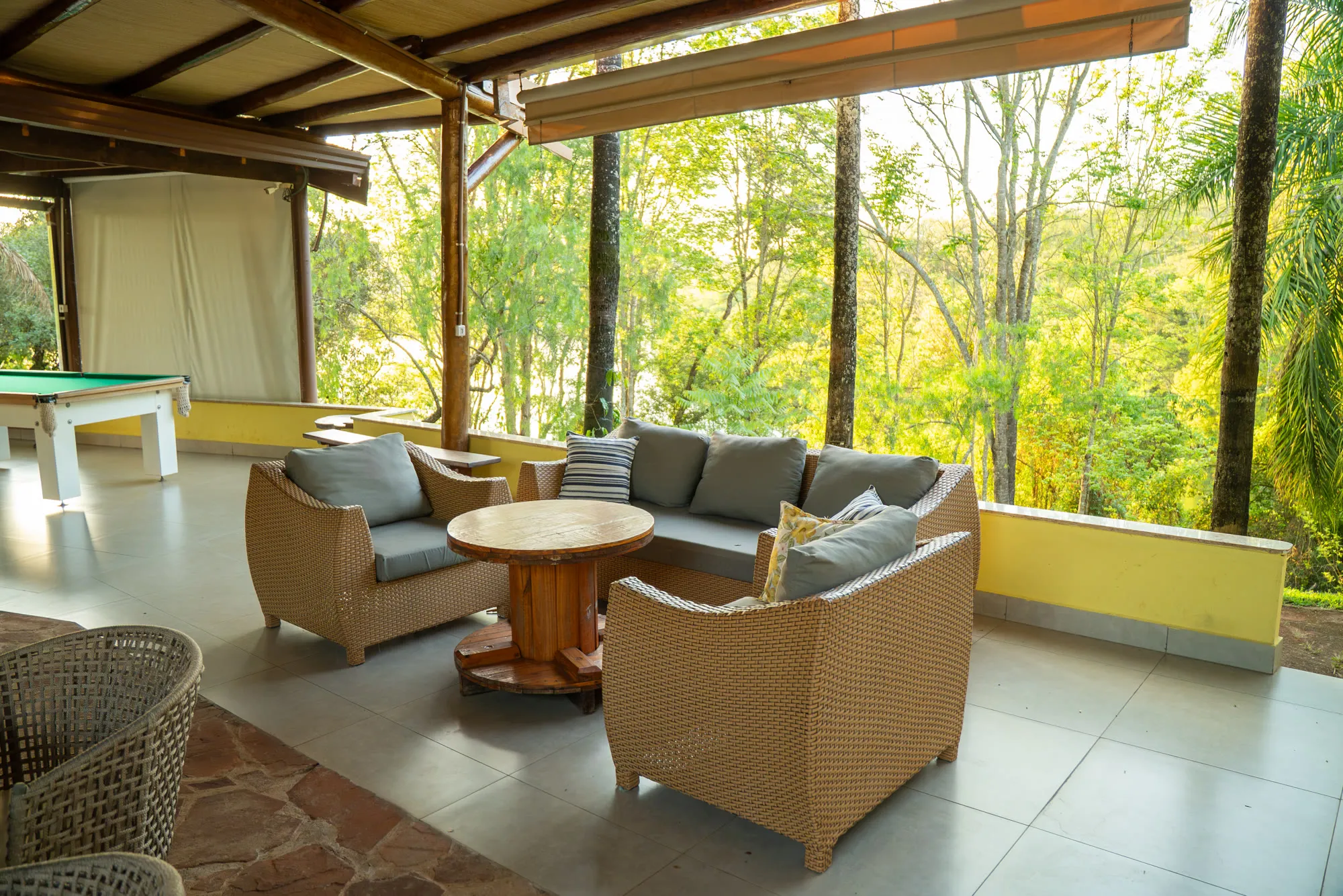 Lounge coberto com sofás de vime, de frente para a mata